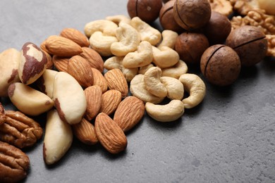 Photo of Mix of different nuts on grey table, closeup. Space for text