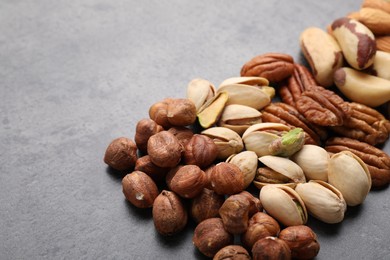 Photo of Mix of different nuts on grey table, closeup. Space for text