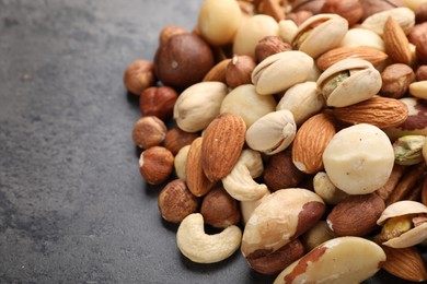 Photo of Mix of different nuts on grey table, closeup. Space for text