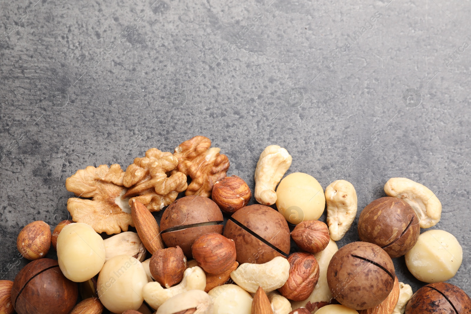 Photo of Mix of different nuts on grey table, flat lay. Space for text