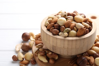 Photo of Mix of different nuts in bowl on white wooden table, closeup