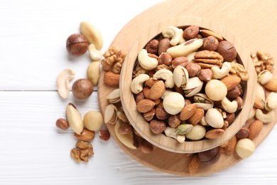 Photo of Mix of different nuts in bowl on white wooden table, top view. Space for text