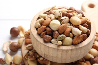 Photo of Mix of different nuts in bowl on white table, closeup