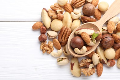 Photo of Mix of different nuts and spoon on white wooden table, flat lay. Space for text