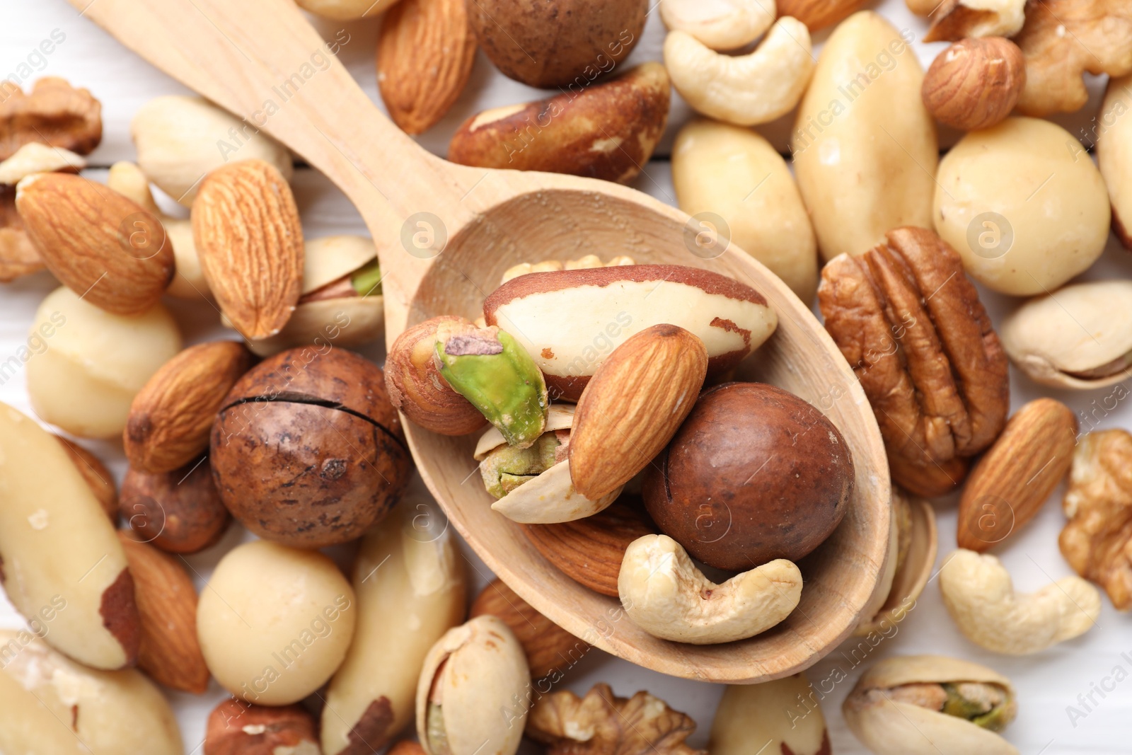Photo of Mix of different nuts and spoon on table, flat lay