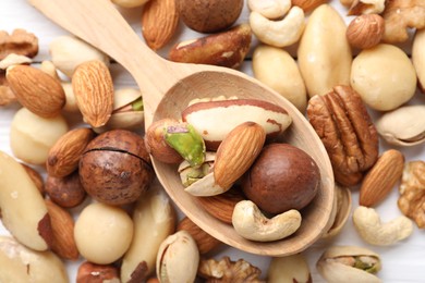 Photo of Mix of different nuts and spoon on table, flat lay