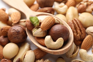 Photo of Mix of different nuts and spoon on table, closeup