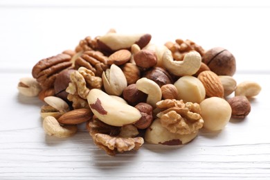 Photo of Mix of different nuts on white wooden table, closeup