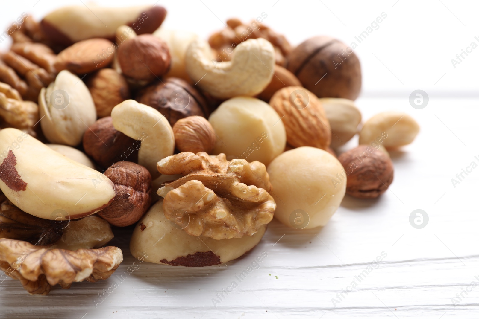 Photo of Mix of different nuts on white wooden table, closeup