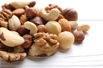 Photo of Mix of different nuts on white wooden table, closeup