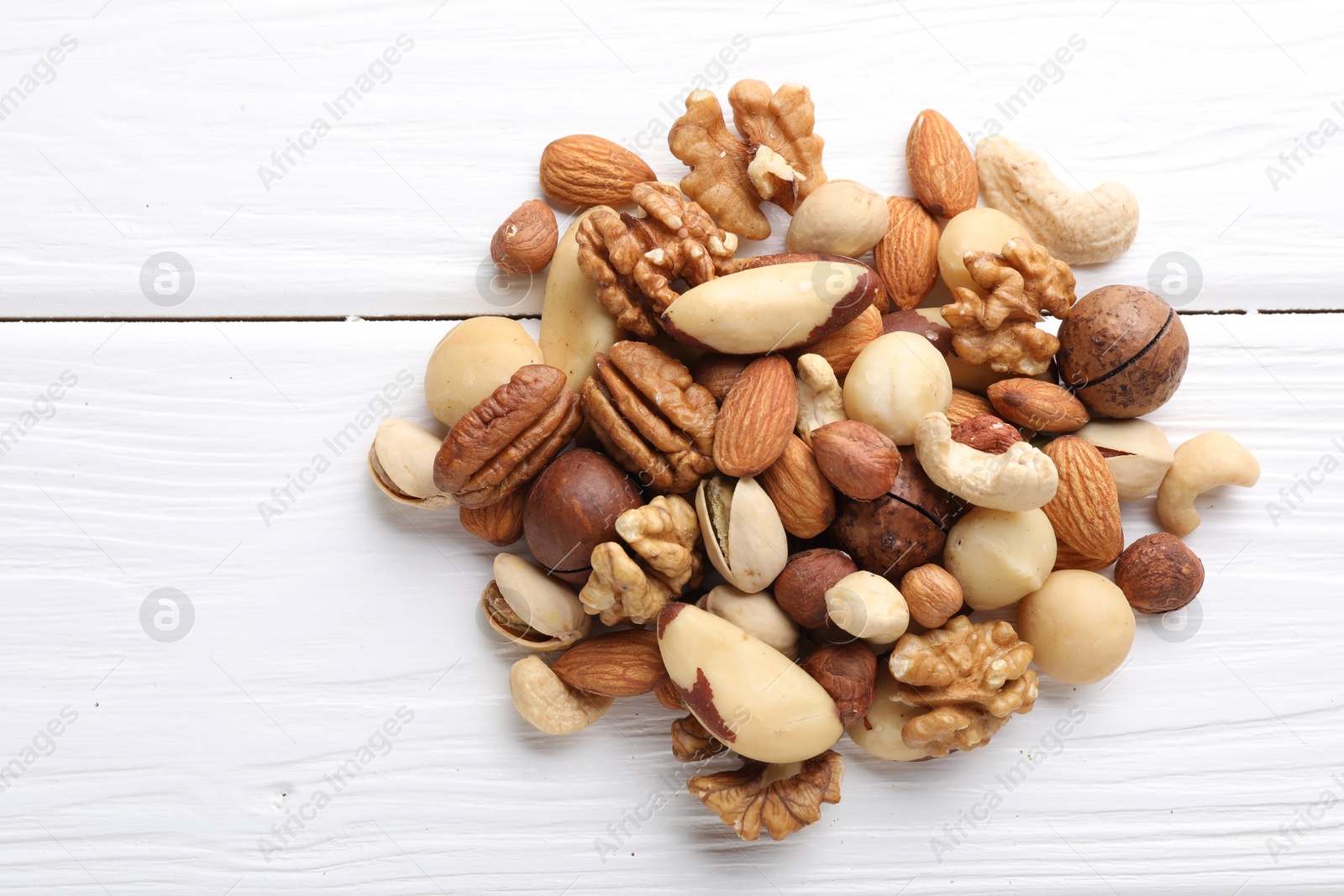 Photo of Mix of different nuts on white wooden table, flat lay. Space for text