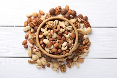 Photo of Mix of different nuts in bowl on white wooden table, flat lay