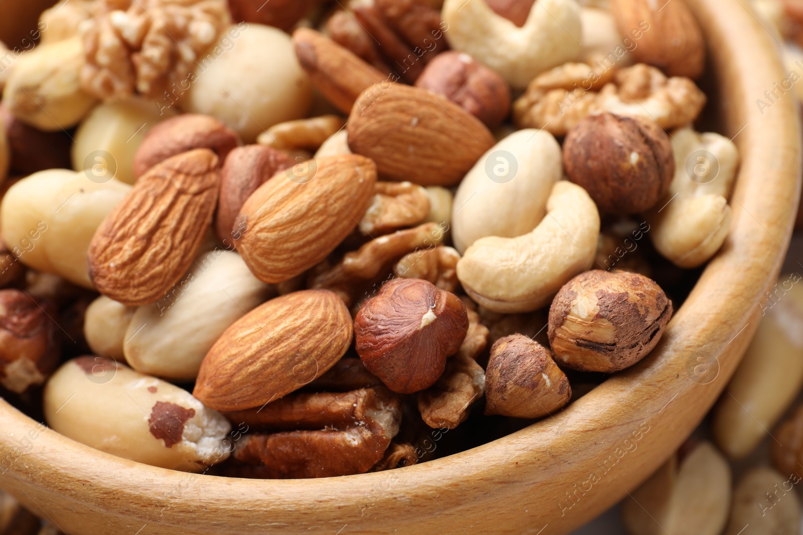 Photo of Mix of different nuts in bowl on table, closeup
