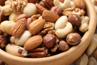 Photo of Mix of different nuts in bowl on table, closeup