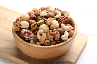 Photo of Mix of different nuts in bowl on white wooden table, closeup