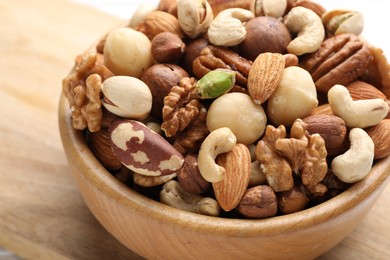 Photo of Mix of different nuts in bowl on table, closeup