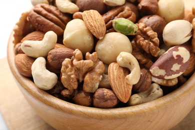 Photo of Mix of different nuts in bowl on table, closeup