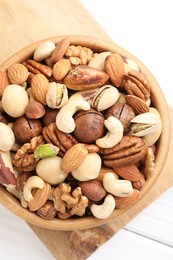 Photo of Mix of different nuts in bowl on white wooden table, top view