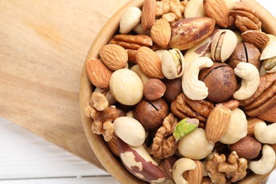 Photo of Mix of different nuts in bowl on white table, top view. Space for text