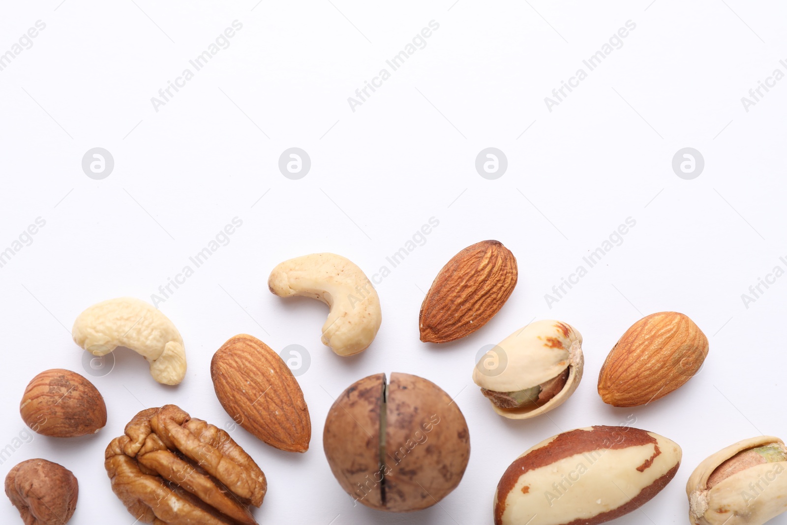 Photo of Mix of different nuts on white background, flat lay. Space for text