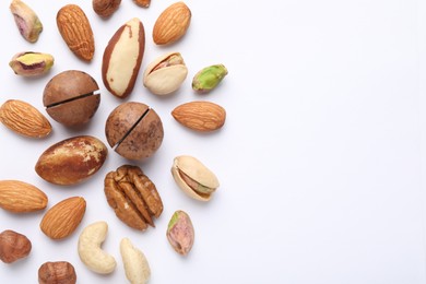 Photo of Mix of different nuts on white background, flat lay. Space for text