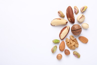 Photo of Mix of different nuts on white background, flat lay. Space for text