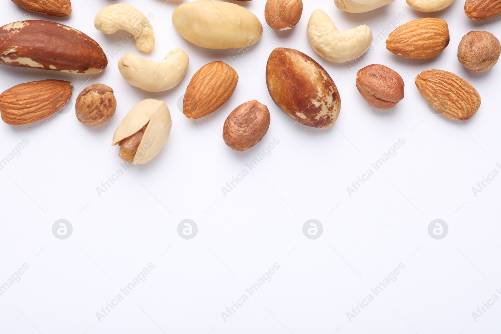 Photo of Mix of different nuts on white background, flat lay. Space for text