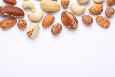 Photo of Mix of different nuts on white background, flat lay. Space for text