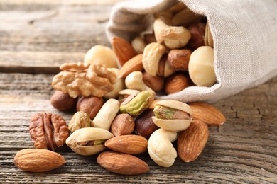 Photo of Mix of different nuts in bag on wooden table, closeup
