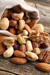 Photo of Mix of different nuts in bag on wooden table, closeup