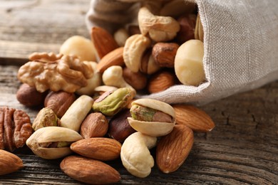 Photo of Mix of different nuts in bag on wooden table, closeup