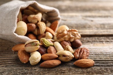 Photo of Mix of different nuts in bag on wooden table, closeup. Space for text