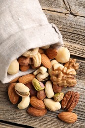 Photo of Mix of different nuts in bag on wooden table, closeup