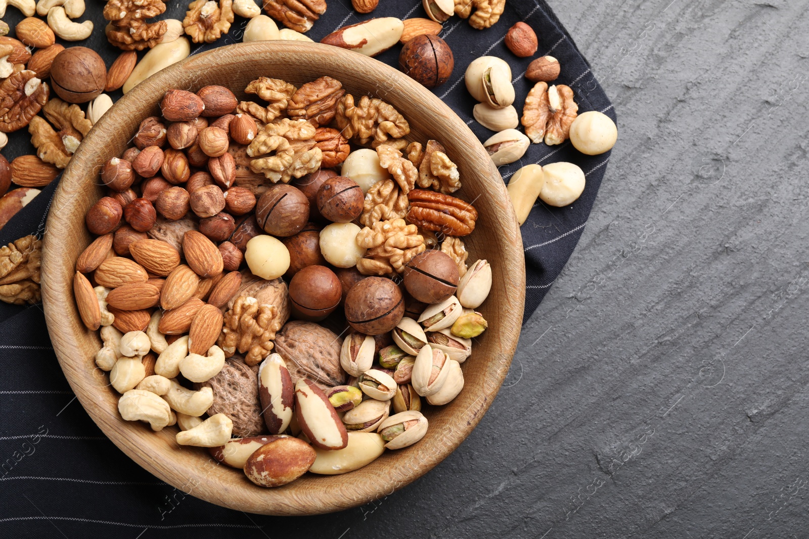 Mix of different nuts in bowl on black table, top view. Space for text Photo of Mix of different nuts in bowl on black table, top view. Space for text