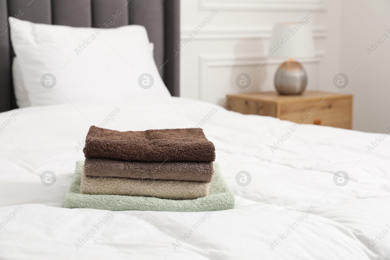 Photo of Stack of terry towels on bed indoors. Space for text