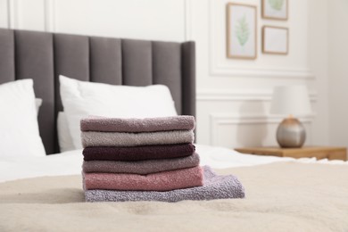 Photo of Stack of terry towels on bed indoors. Space for text