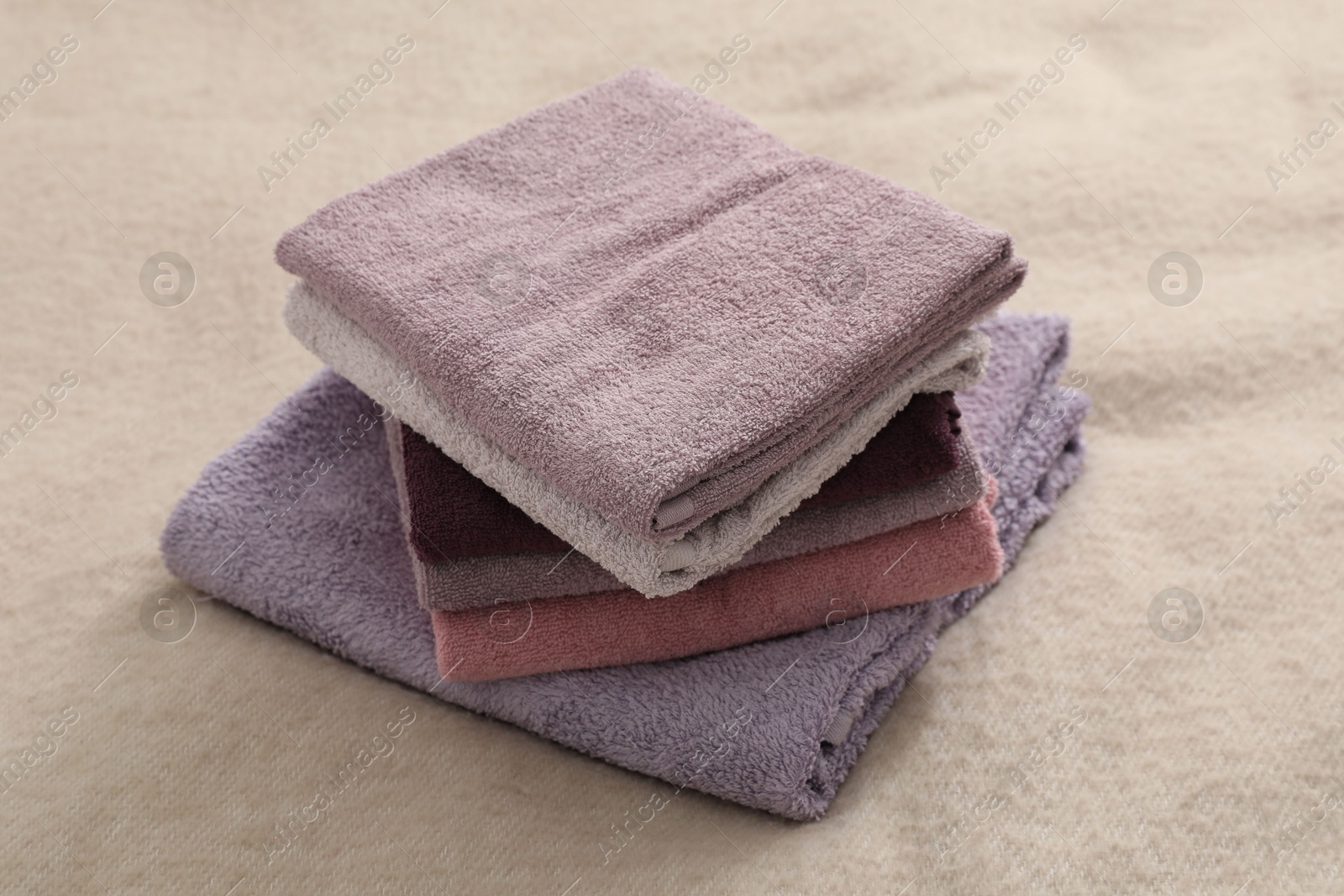 Photo of Stack of terry towels on beige blanket, closeup