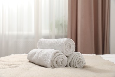 Photo of Rolled white towels on bed indoors, closeup