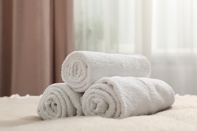 Photo of Rolled white towels on bed indoors, closeup