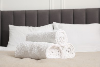 Photo of Rolled white towels on bed indoors, closeup