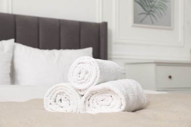 Photo of Rolled white towels on bed indoors, closeup