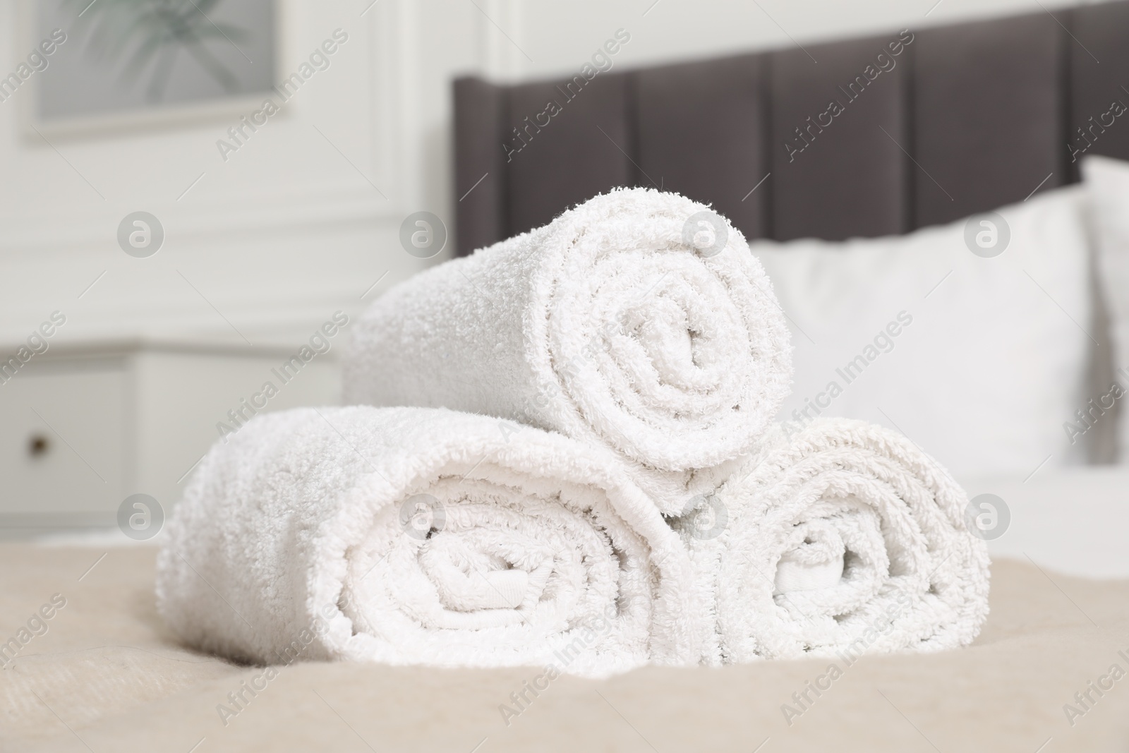 Photo of Rolled white towels on bed indoors, closeup
