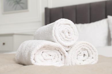 Photo of Rolled white towels on bed indoors, closeup