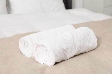 Photo of Rolled white towels on bed indoors, closeup