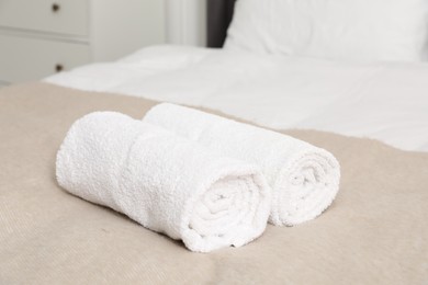 Photo of Rolled white towels on bed indoors, closeup