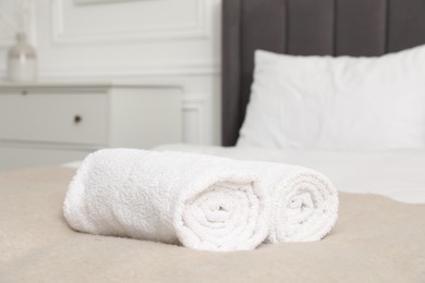 Photo of Rolled white towels on bed indoors, closeup