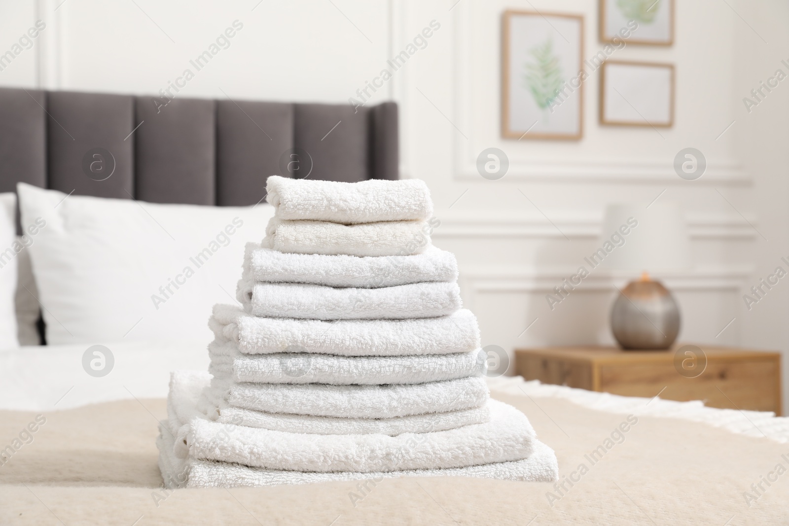 Photo of Stack of white terry towels on bed indoors