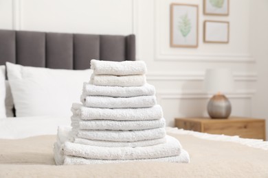 Photo of Stack of white terry towels on bed indoors