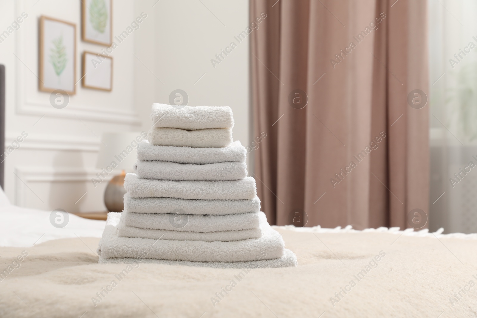 Photo of Stack of white terry towels on bed indoors