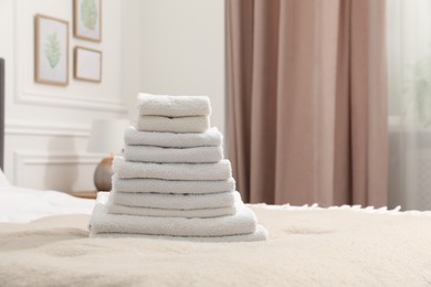 Photo of Stack of white terry towels on bed indoors